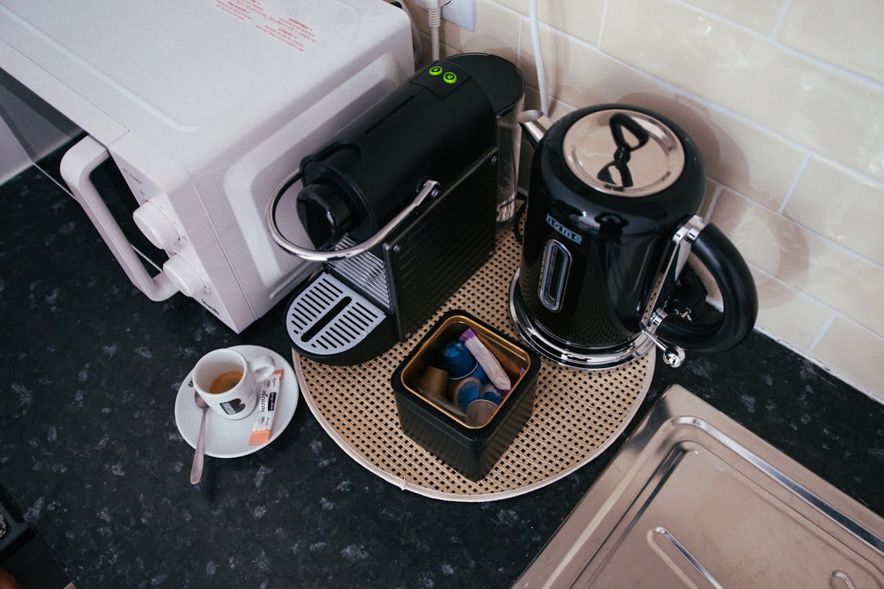 Top view of a kitchen counter featuring coffee machine, kettle, and espresso cup.